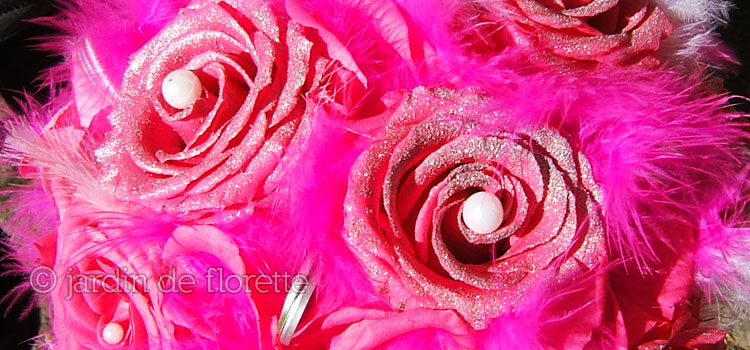Zoom sur un bouquet de mariée éternel à base de roses éternelles roses pailletées et de plumes fuchsias et blanches